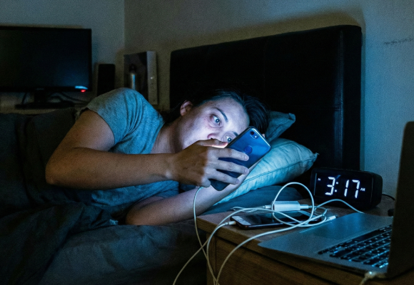 Person struggling to sleep while looking at a phone screen